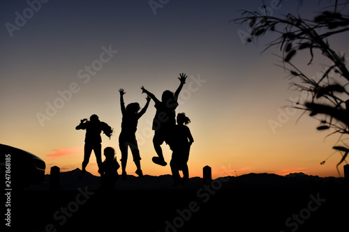 Silhouette of a jumping family at sunset.