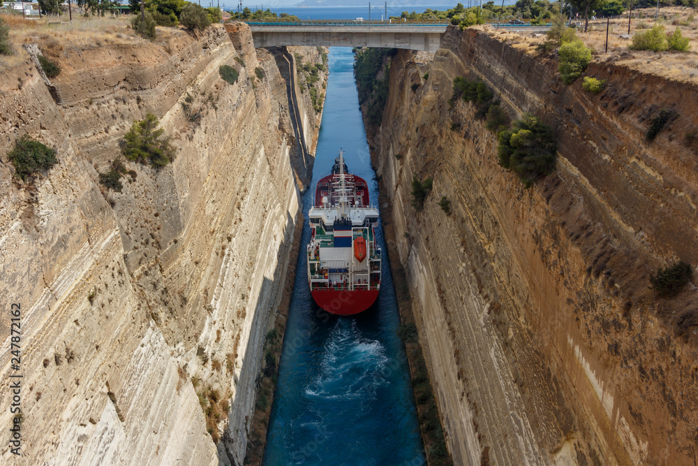 Large ship passing through Corinth canal. The Corinth Canal connects the Gulf of Corinth with the Saronic Gulf in the Aegean Sea. It separates Peloponnese from the Greek mainland.