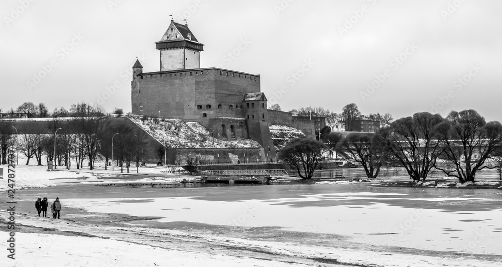 Narva River Promenade, Narva castle and river on a snowy winter day. Black and white.