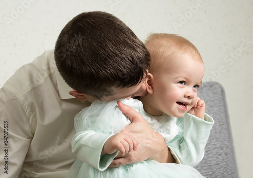 father plays with her little daughter, tickles her neck with kisses