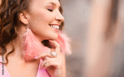 close-up portrait of a young beautiful sexy girl with curly hair in a pink feather dress  smiling lifestyle on a street in sunny day