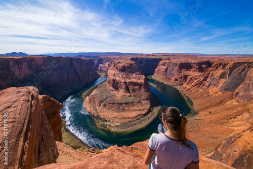 Young woman sitting in the edge of the Horseshoe Bend admiring the landscape. Page, Arizona, United States. © Andrea