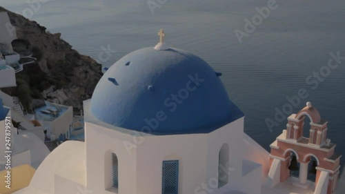 Iconic blue church dome and pink church bell in Oia, Santorini. Overlooking the picturesque Santorini seascape. photo