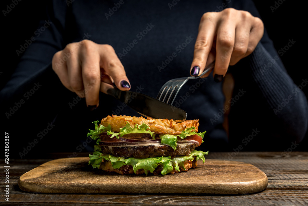 Healthy lifestyle, proper nutrition. Female hands cut a useful rice burger with vegetables, herbs and cutlet on a wooden board