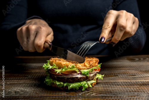 Healthy lifestyle  proper nutrition. Female hands cut a useful rice burger with vegetables  herbs and cutlet on a wooden board