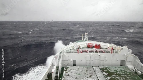 Research vessel cruising in the stormy seas of the southern ocean with waves breaking at the hull of the ship