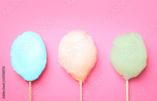 Sticks with different colorful yummy cotton candy on pink background, flat lay