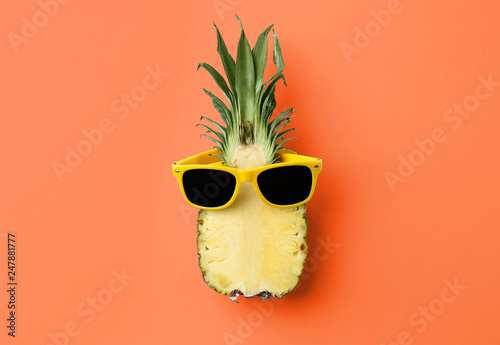 Funny pineapple with sunglasses on orange background, top view