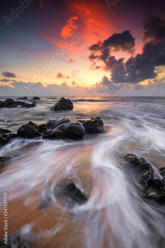 A scenery of sunrise with amazing unique rock formation and beautiful flow of wave at Kemasik beach, Terangganu Malaysia. Soft focus during long exposure shot.