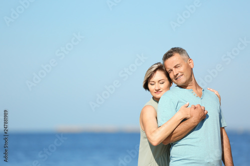Happy mature couple at beach on sunny day