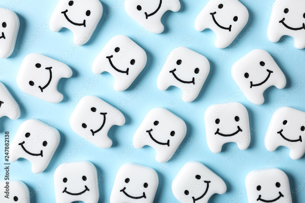 Many small plastic teeth with cute faces on color background, top view Many small plastic teeth with cute faces on color background, top view