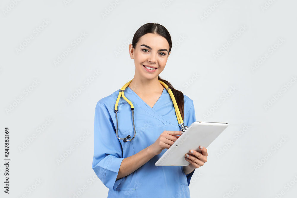 Portrait of medical assistant with stethoscope and tablet on light background Portrait of medical assistant with stethoscope and tablet on light background