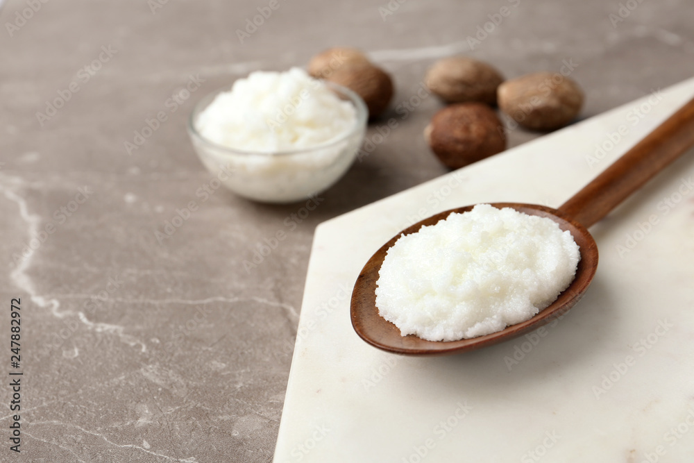 Shea butter in wooden spoon and bowl with nuts on grey background Shea butter in wooden spoon and bowl with nuts on grey background