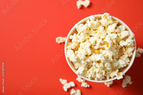 Fresh tasty popcorn and cup on color background, top view with space for text. Cinema snack