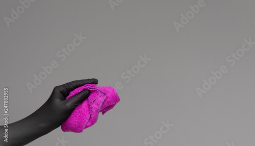 A hand in a rubber glove holds a bright microfiber duster on a neutral background. Сoncept of bright spring, spring cleaning. © Елена Нестерова