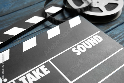 Clapperboard and reel on wooden table, closeup. Cinema production