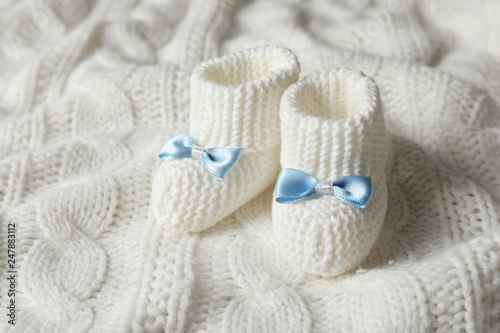 Handmade baby booties on soft knitted plaid