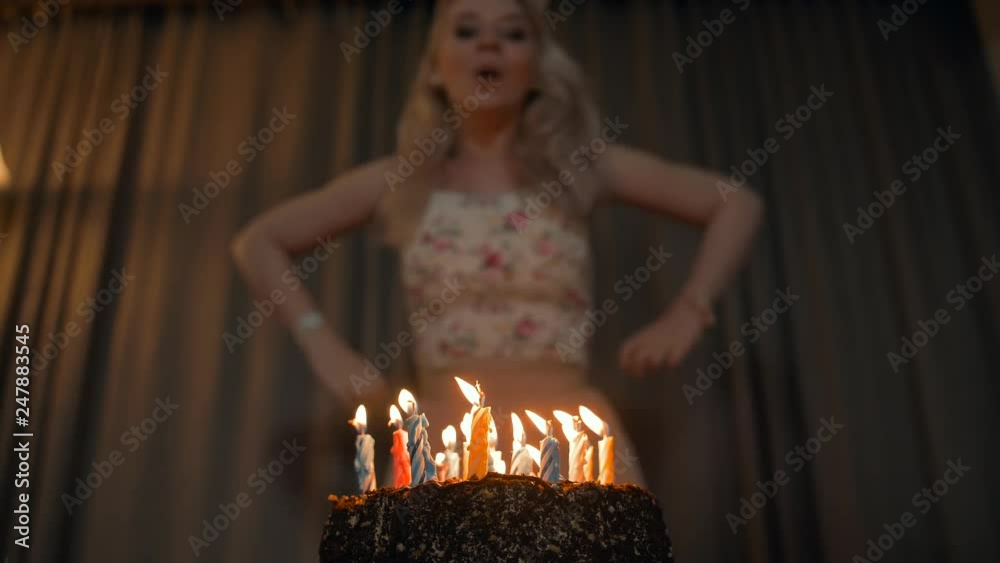 Beautiful woman blowing out candles on a festive cake.