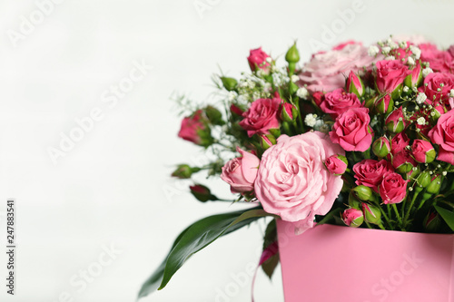 Beautiful bouquet of flowers in paper gift box on light background. Space for text