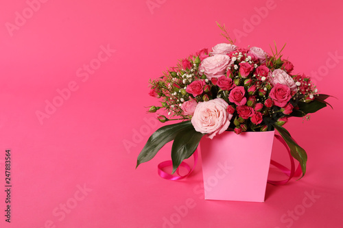 Beautiful bouquet of flowers in paper gift box on color background. Space for text