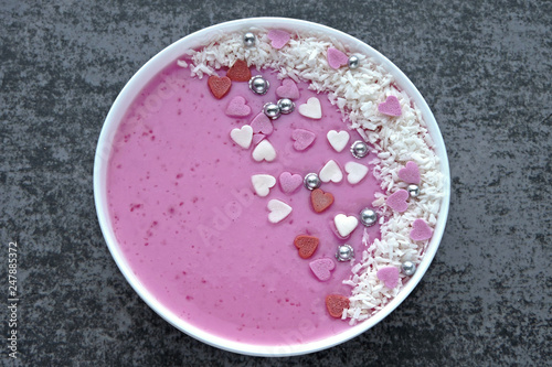 Happy Valentine's breakfast bowl. Pink smoothie bowl with decorations hearts.