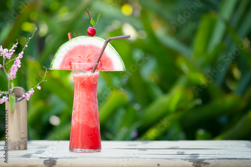 Fresh watermelon smoothie with straw on green background