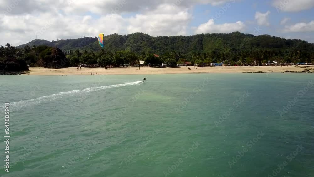 Solo kitesurfing in the tropical location near the beach with hills