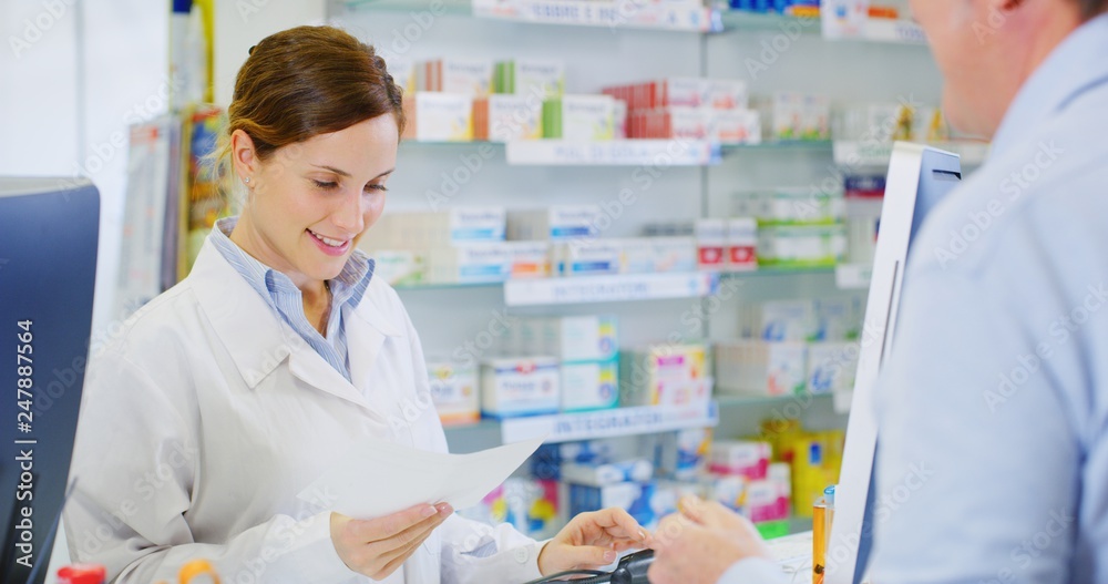 Portrait of young woman pharmacist handing over prescribed medicines to a patient in drugs store. Concept of profession, medicine and healthcare, medical education,pharmaceutical sector
