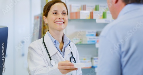 Portrait of young woman pharmacist handing over prescribed medicines to a patient in drugs store. Concept of profession, medicine and healthcare, medical education,pharmaceutical sector