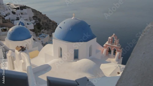 Iconic blue church domes and pink church bell in Oia, Santorini. Overlooking the majestic Santorini seascape. photo