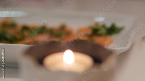 Close-up rack focus from a small candle to a plate of salmon Sashimi photo