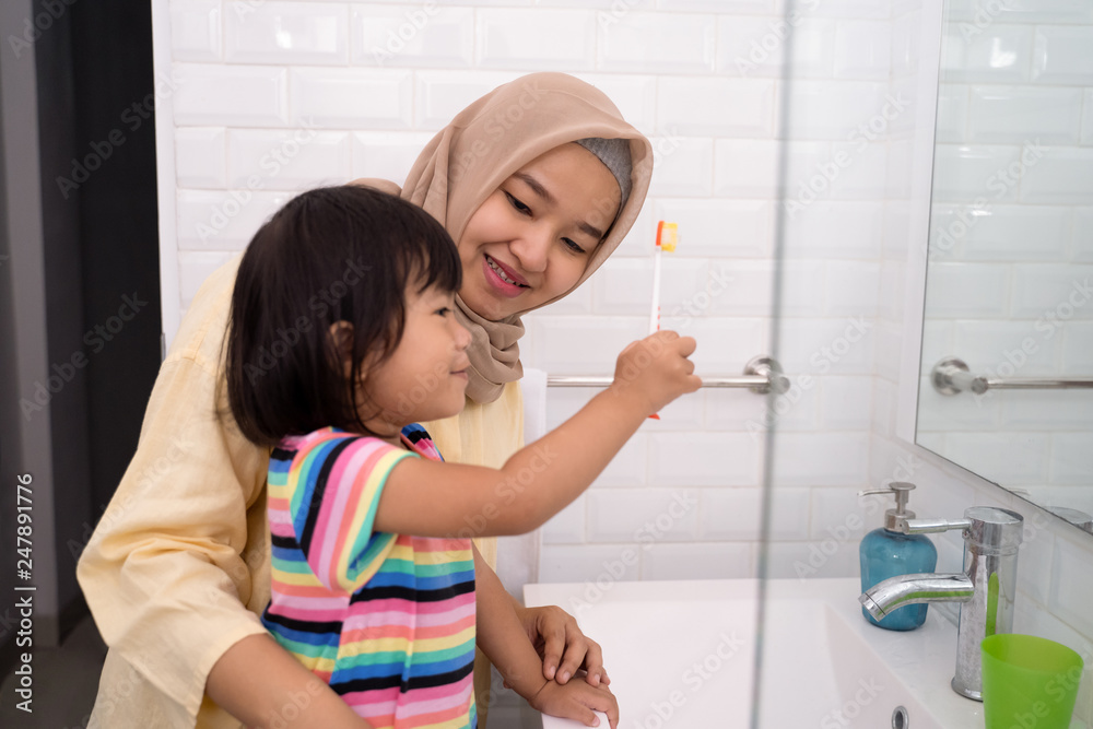 muslim mother and her daughter brushing teeth together before bed muslim mother and her daughter brushing teeth together before bed