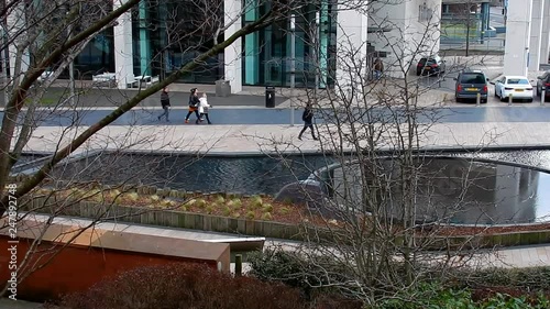 Water feature pond in middle of city business centre. People passing on concrete pathway. photo