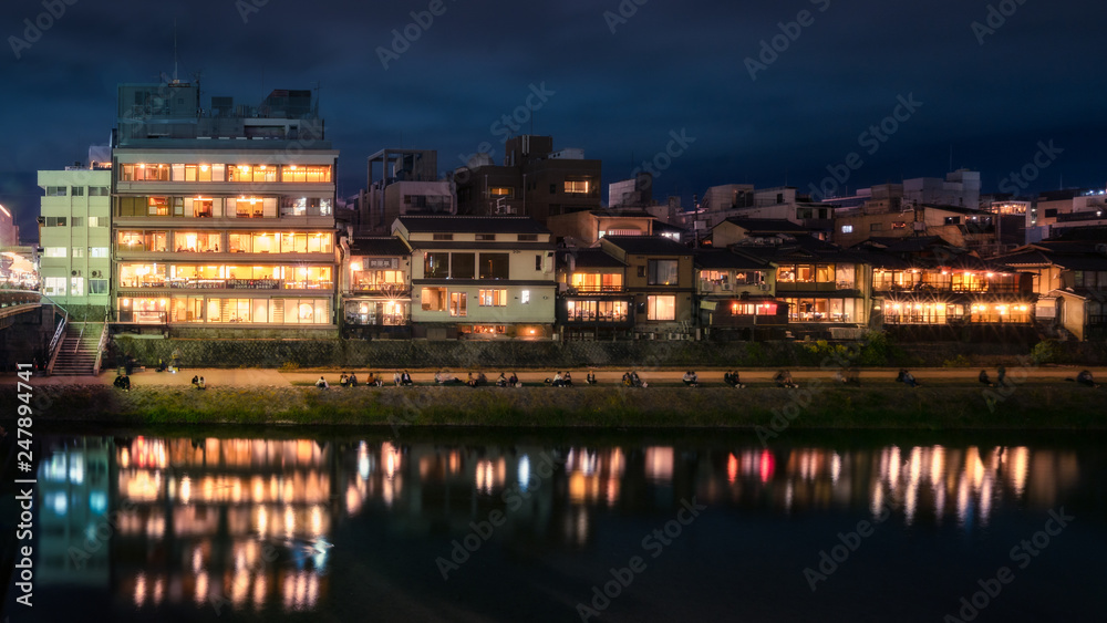 Promenade at night along Kamo River next to Shijoo Bridge in Gion District, Kyoto, Japan.