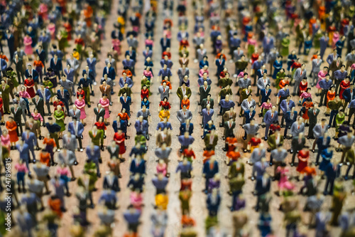Rows of miniature people standing in line representing image of population or crowd.