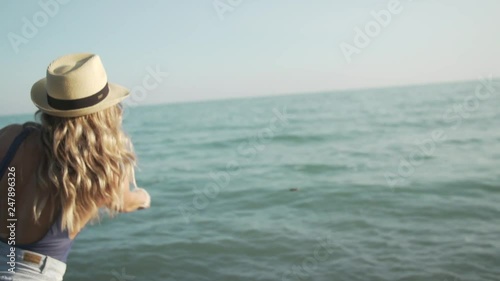 A girl throws a rock into the water at sunset. photo