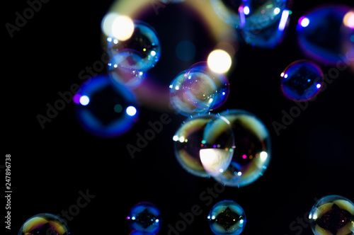 beautiful colorful soap bubbles float in the dark.