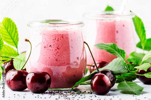 Pink cherry milkshake or smoothies with fresh berry and chia seeds, white stone kitchen background, place for text, top view