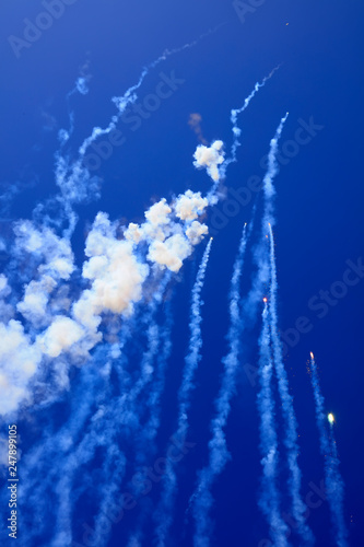 Fireworks explode, smoke in the blue sky
