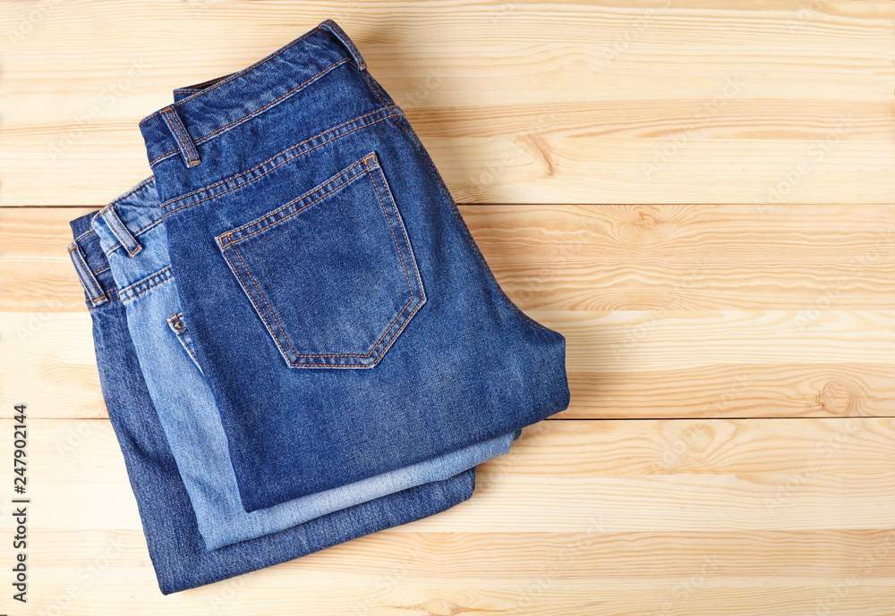 A stack of folded jeans on wooden background. A stack of folded jeans on wooden background.