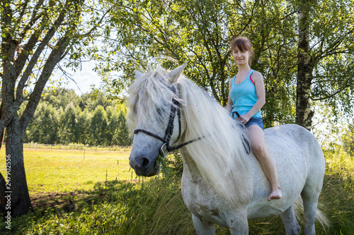 Young girl and white horse on nature in summer