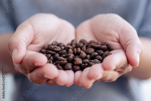 Closeup image of a woman's hands holding and showing coffee beans