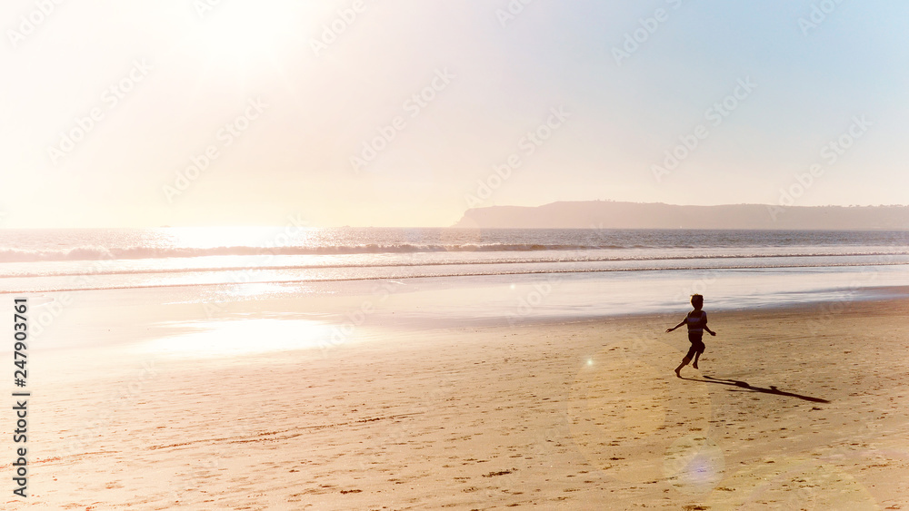 ocean beach at sunset and boy running along shore of pacific ocean seaside at san diego city in california usa retro vintage style photo vacation happy childhood panoramic scene