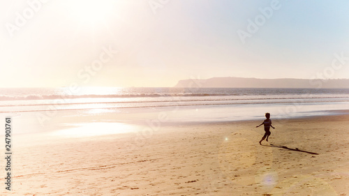 ocean beach at sunset and boy running along shore of pacific ocean seaside at san diego city in california usa retro vintage style photo vacation happy childhood panoramic scene
