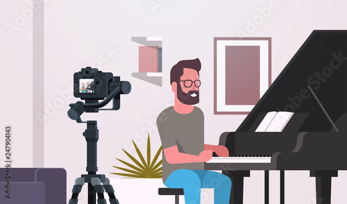 guy musical blogger recording video on camera man playing classical piano music blog concept modern apartment interior closeup horizontal
