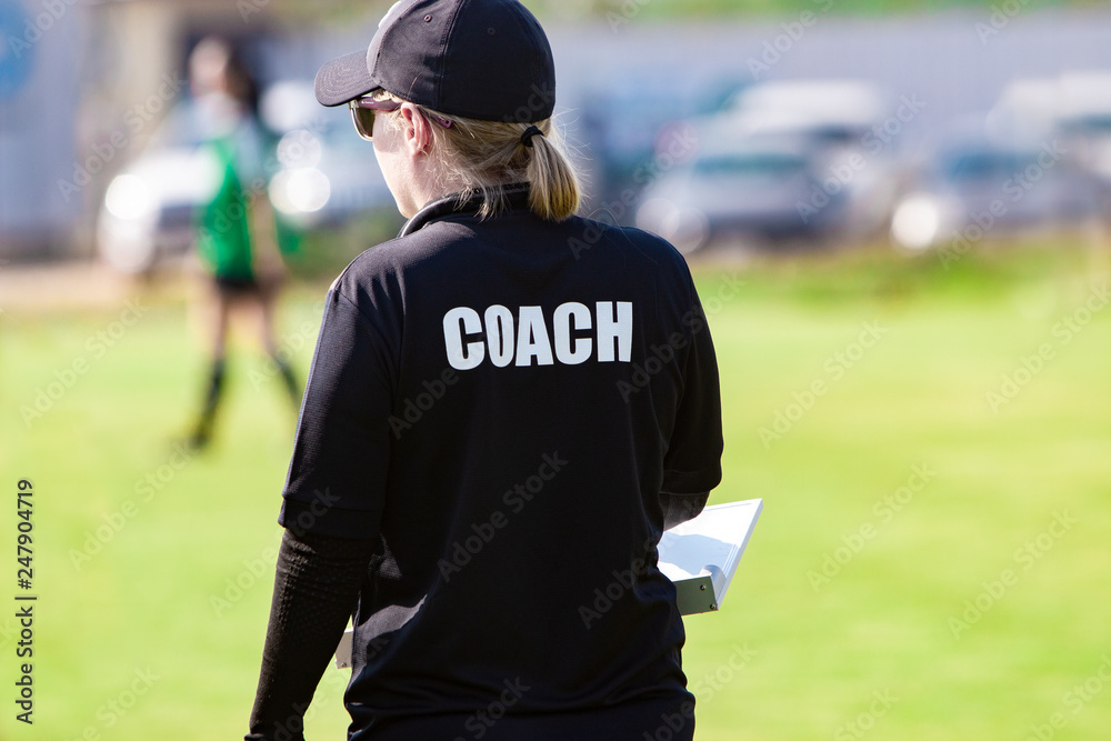 Φωτογραφία Back view of female football coach in black COACH shirt at an outdoor sport fiel