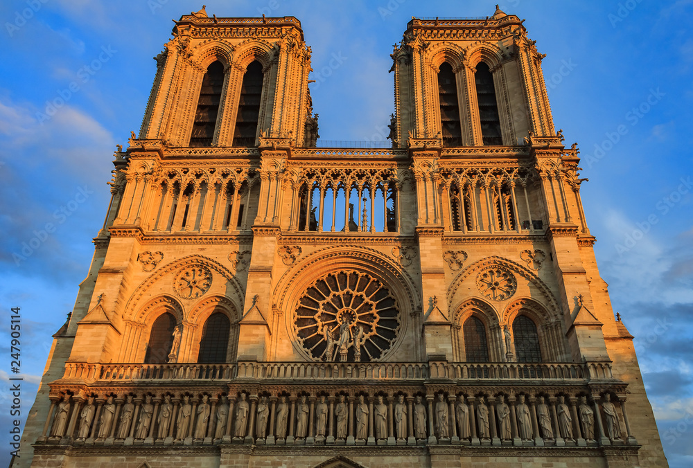 Details of the southern facade of Notre Dame de Paris Cathedral facade with the oldest rose window and ornate tracery in the warm light of sunset
