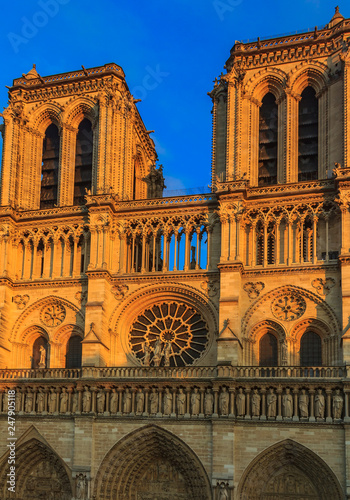 Details of the main facade of Notre Dame de Paris Cathedral facade with the oldest rose window and ornate tracery in the warm light of sunset