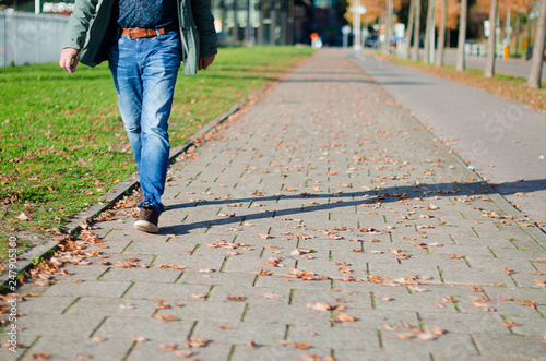 a man in jeans and a jacket is walking along a footpath