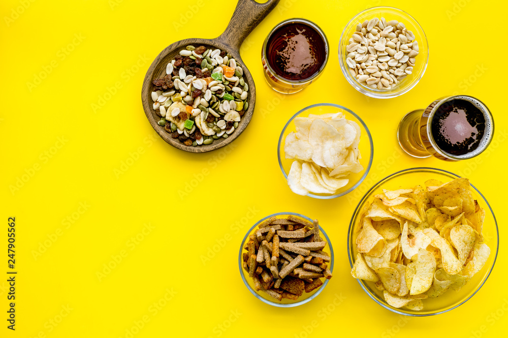 Fast food for TV watching. Snacks on desk.  Chips, nuts, rusks and beer on yellow background top view copy space